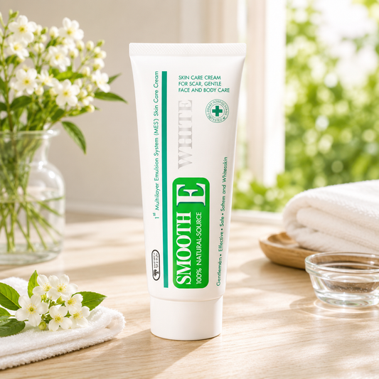 Tube of Smooth E cream on a wooden surface with flowers and towels in the background